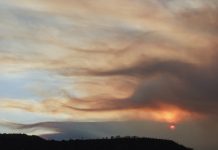 Fourth firefighter dies from injuries sustained during June wildfire in Colorado Sunset over rolling hills with orange/pink clouds lit by the setting sun on the horizon, silhouetted hills below