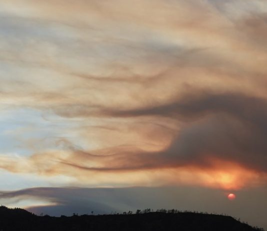 Fourth firefighter dies from injuries sustained during June wildfire in Colorado Sunset over rolling hills with orange/pink clouds lit by the setting sun on the horizon, silhouetted hills below