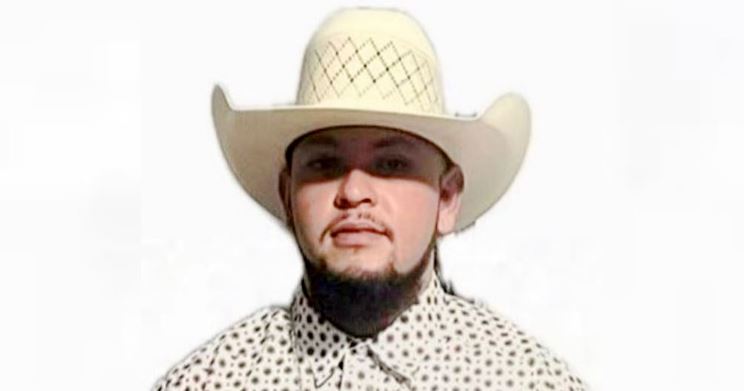 Man wearing a white cowboy hat and patterned shirt, facing the camera against a white background.