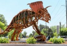 SLC adding Jordan River Parkway to public art collection Large rusty metal dragon sculpture on a traffic circle in a suburban street.