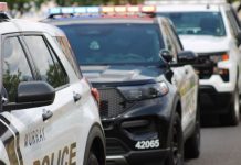 Row of police SUVs with flashing emergency lights parked on a street, showing police markings.