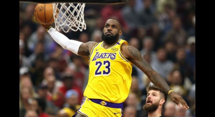 LeBron James of the Los Angeles Lakers wearing #23 dunks toward the hoop during a crowded game.