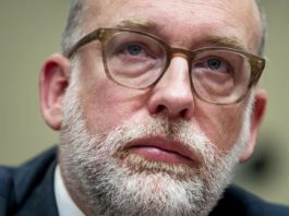 Trump administration admits it canceled grants from Harris voters Close-up portrait of a middle-aged man with a gray beard and brown glasses, looking upward thoughtfully.