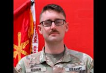 Southern Utah University MBA student among US soldiers killed in Iranian missile, drone strikes in Jordan U.S. Army soldier in camouflage uniform with name tag Feehan, black-framed glasses, and mustache, posed in front of a red backdrop and flag.