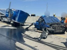 UHP releases name of driver killed in Taylorsville collision with semi Highway crash scene with a crushed blue car and a blue semi-trailer, fluids spilled on the road, and first responders in orange vests nearby.