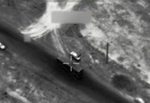 U.S., Iran trade attacks amid mixed signals on diplomacy Grayscale aerial view of a car on a curved road with a targeting crosshair overlay.