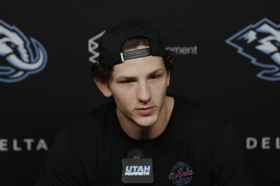 Utah-Mammoth-sign-defenseman-John-Marino-to-54M-extension Young man with a backward cap speaks into a microphone at a press conference, backdrop with sponsor logos behind him.