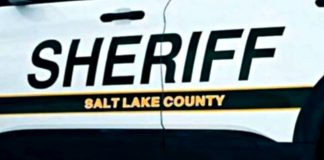 Close-up of a white sheriff patrol vehicle with the word SHERIFF and Salt Lake County branding on the side panel.