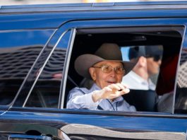 Church pres. Dallin H. Oaks appears in Days of ’47 parade Elderly man wearing a brown cowboy hat and glasses waves from the window of a blue car.