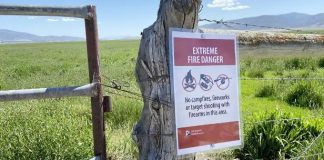 Sign attached to a weathered fence post reading Extreme Fire Danger; warns no campfires, fireworks, or shooting in the area.